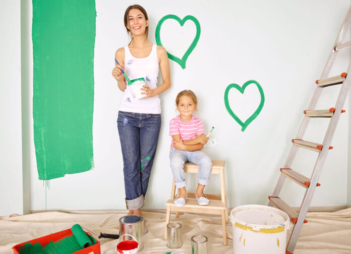 Mother and daughter painting green hearts on wall