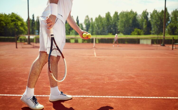 Tennis player holding ball on court about to serve