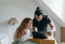 a young couple browsing laptop on cardboard box