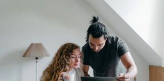 a young couple browsing laptop on cardboard box