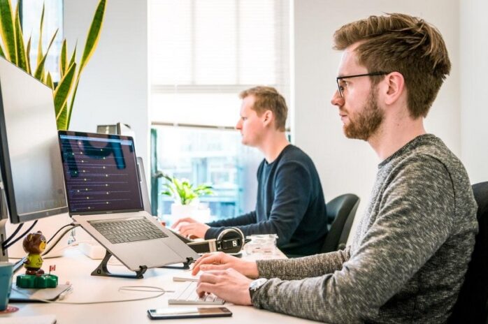 An office employee working on his laptop next to his colleague