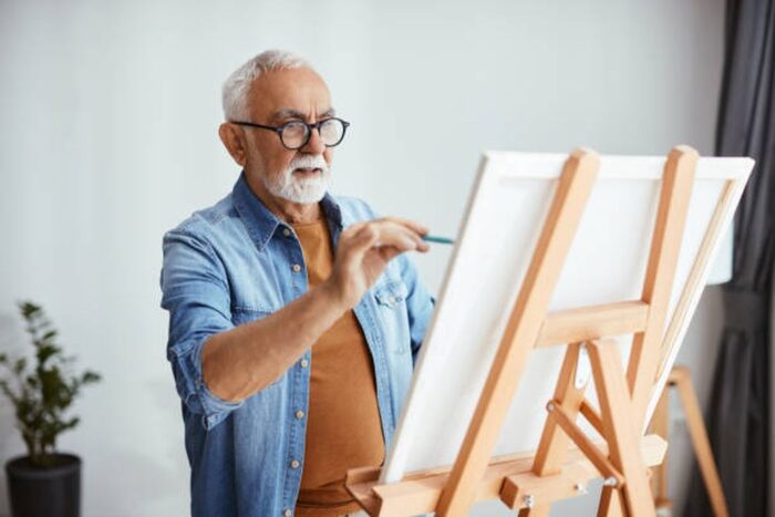 Mature man creating a new painting on canvas at home