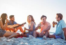 A group of friends celebrating on a beach with music, drinks and BBQ