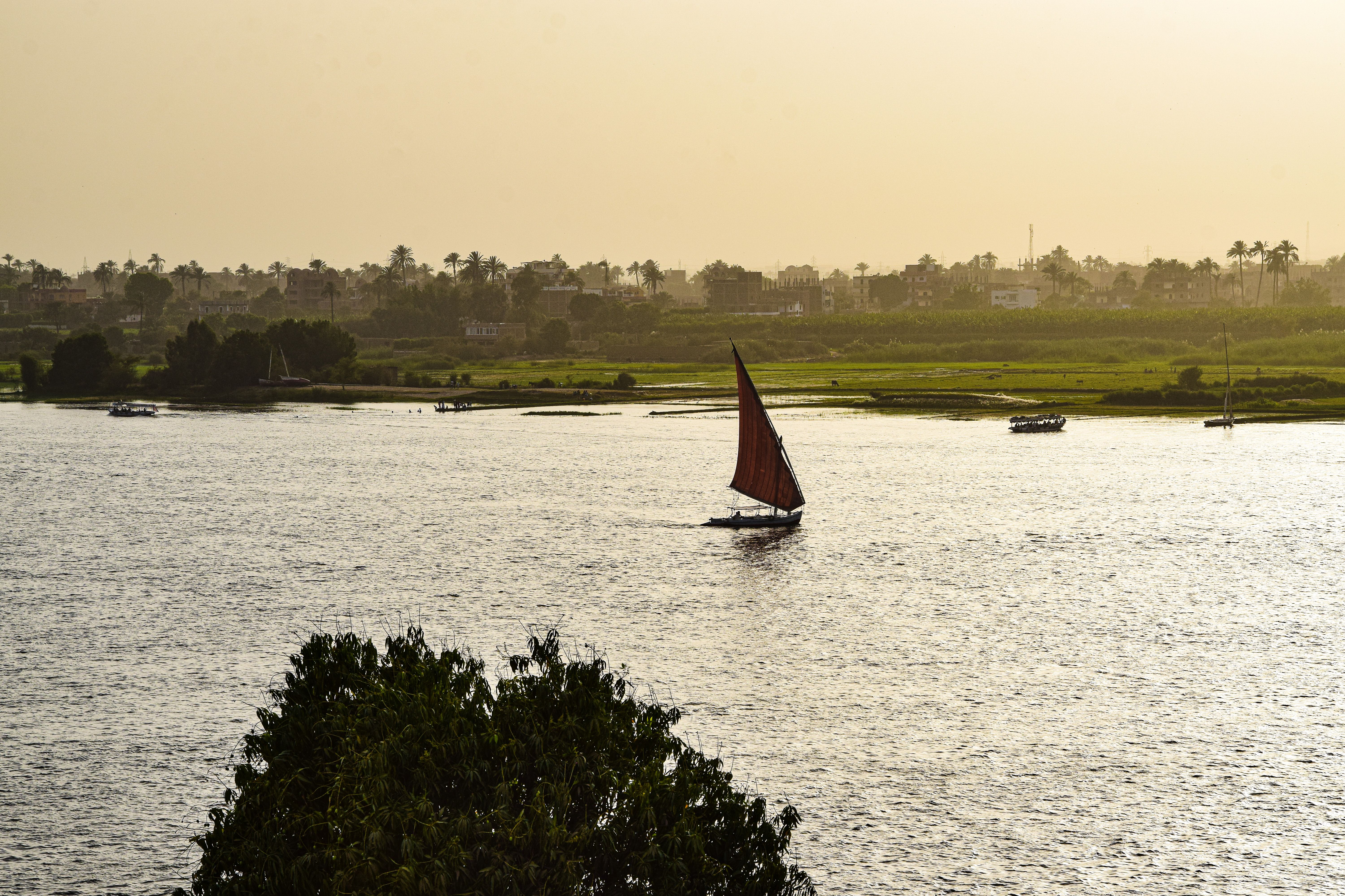 A traditional sailboat glides on the Nile River in Luxor, Egypt, as the sun sets